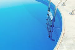 Nahaufnahme eines Teils des Swimmingpools mit einer Edelstahlleiter und des blauen Wassers auf Sonnenuntergang Sommerferien, Feie stockfoto Nahaufnahme eines Teils des Swimmingpools mit einer Edelstahlleiter und des blauen Wassers auf Sonnenuntergang Sommerferien, Feie stockfoto