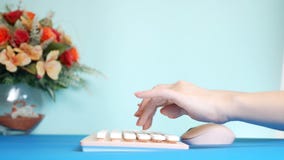 Nahaufnahme stilvolle gr??ende Videokarte weibliche H?nde schreiben auf einer rosa Tastatur, nahe bei einer Blume Auf einem Blau stockfotografie Nahaufnahme stilvolle gr??ende Videokarte weibliche H?nde schreiben auf einer rosa Tastatur, nahe bei einer Blume Auf einem Blau stockfotografie