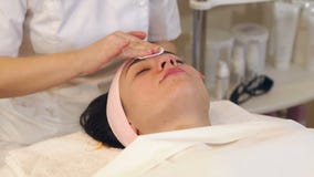 Nahaufnahmekosmetiker in den schwarzen Handschuhen wischen Gesicht mit micellaren Wasser des Wattest?bchens ab stock video Nahaufnahmekosmetiker in den schwarzen Handschuhen wischen Gesicht mit micellaren Wasser des Wattest?bchens ab stock video