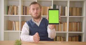 Nahaufnahmeporträt des jungen kaukasischen Geschäftsmannes, der die Tablette verwendet und grünen Farbenreinheitsschirm zur Kamer stock footage Nahaufnahmeporträt des jungen kaukasischen Geschäftsmannes, der die Tablette verwendet und grünen Farbenreinheitsschirm zur Kamer stock footage