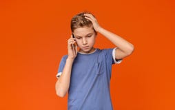 Nastoletni chłopak opowiada na telefonie, trzyma rękę na głowie w stresie obraz stock Nastoletni chłopak opowiada na telefonie, trzyma rękę na głowie w stresie obraz stock