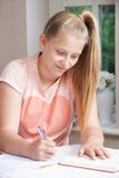Nastoletnia dziewczyna robi pracie domowej przy stołem obrazy stock Nastoletnia dziewczyna robi pracie domowej przy stołem obrazy stock