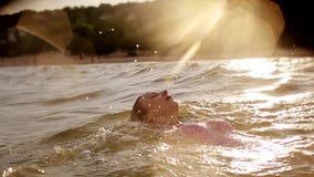 A natação da jovem mulher no mar nela para trás durante o por do sol que faz a água espirra no movimento lento backstroke vídeos de arquivo A natação da jovem mulher no mar nela para trás durante o por do sol que faz a água espirra no movimento lento backstroke vídeos de arquivo
