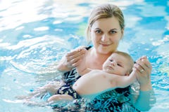 Natação de meia idade feliz da mãe com o bebê adorável bonito na piscina fotos de stock Natação de meia idade feliz da mãe com o bebê adorável bonito na piscina fotos de stock