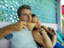Young beautiful and happy mixed ethnicity couple in love relaxed together with handsome Caucasian man drinking coffee and royalty free stock photo Young beautiful and happy mixed ethnicity couple in love relaxed together with handsome Caucasian man drinking coffee and royalty free stock photo
