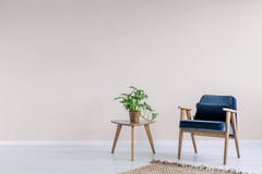 Navy blue armchair with wooden frame in a trendy living room interior with an empty pink wall and copy space for a bookcase. Real royalty free stock images Navy blue armchair with wooden frame in a trendy living room interior with an empty pink wall and copy space for a bookcase. Real royalty free stock images