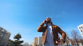 Negociaciones nerviosas jovenes de un hombre emocionalmente sobre varios teléfonos Un individuo con una barba y los vidrios que h Negociaciones nerviosas jovenes de un hombre emocionalmente sobre varios teléfonos Un individuo con una barba y los vidrios que h