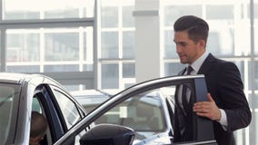Negociante do veículo que mostra o carro novo video estoque Negociante do veículo que mostra o carro novo video estoque
