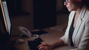 Neigung-oben geschossen von der ernsten jungen Frau, die an dem Computer schreibt und betrachtet den Schirm sitzt am Worktable al stock footage Neigung-oben geschossen von der ernsten jungen Frau, die an dem Computer schreibt und betrachtet den Schirm sitzt am Worktable al stock footage