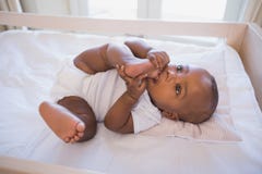 Neonato adorabile che si trova in sua greppia che mastica piede immagine stock Neonato adorabile che si trova in sua greppia che mastica piede immagine stock
