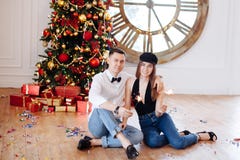Nette intelligente Paare mit der Wunderkerze, die zu Hause nahe verziertem Weihnachtsbaum vor Partei flirtet stockfoto Nette intelligente Paare mit der Wunderkerze, die zu Hause nahe verziertem Weihnachtsbaum vor Partei flirtet stockfoto