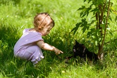 Nettes Baby spielt mit einer schwarzen Katze im Park Stockbild Nettes Baby spielt mit einer schwarzen Katze im Park Stockbild