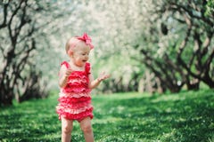 Nettes glückliches Baby in gehendem im Frühjahr Garten des lustigen rosa Spielanzugs im Freien lizenzfreies stockfoto Nettes glückliches Baby in gehendem im Frühjahr Garten des lustigen rosa Spielanzugs im Freien lizenzfreies stockfoto