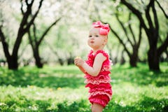 Nettes glückliches Baby in gehendem im Frühjahr Garten des lustigen rosa Spielanzugs im Freien lizenzfreie stockbilder Nettes glückliches Baby in gehendem im Frühjahr Garten des lustigen rosa Spielanzugs im Freien lizenzfreie stockbilder