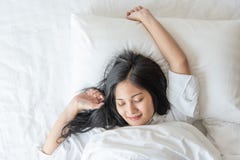 Nettes hübsches Asiatinlächeln und glücklich auf Bett im Schlafzimmer stockbild Nettes hübsches Asiatinlächeln und glücklich auf Bett im Schlafzimmer stockbild