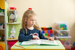 Nettes kleines Mädchen, das Hausarbeit, ein Buch, Färbungsseiten, ein Schreiben und eine Malerei lesend tut Unterricht im Kinderg lizenzfreies stockfoto Nettes kleines Mädchen, das Hausarbeit, ein Buch, Färbungsseiten, ein Schreiben und eine Malerei lesend tut Unterricht im Kinderg lizenzfreies stockfoto