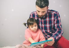 Nettes kleines Mädchen und ihr hübscher Vater verwenden eine digitale Tablette und ein Lächeln und zu Hause sitzen lizenzfreies stockfoto Nettes kleines Mädchen und ihr hübscher Vater verwenden eine digitale Tablette und ein Lächeln und zu Hause sitzen lizenzfreies stockfoto