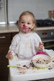 Nettes schmutziges kleines Mädchen, das gesunden Brei isst Lizenzfreies Stockbild Nettes schmutziges kleines Mädchen, das gesunden Brei isst Lizenzfreies Stockbild