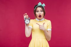 Nettes überraschtes Pinupmädchen, das auf Wecker zeigt stockbild Nettes überraschtes Pinupmädchen, das auf Wecker zeigt stockbild