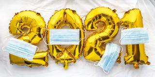 2021 new year numbers golden foil balloons on white sheet with face masks. Saying goodbye to Covid