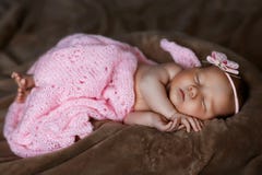 Newborn baby girl sleeping cute, covered with soft pink scarf, neatly folded under a pen with a small head with a pink bow, set stock photo Newborn baby girl sleeping cute, covered with soft pink scarf, neatly folded under a pen with a small head with a pink bow, set stock photo