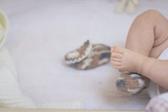 Newborn ноги младенца закрывают вверх в носках шерстей на белом одеяле Младенец в шпаргалке Один носок извлечется из ноги и лож стоковая фотография Newborn ноги младенца закрывают вверх в носках шерстей на белом одеяле Младенец в шпаргалке Один носок извлечется из ноги и лож стоковая фотография