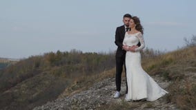 Newly married wedding couple stand near a cliff overlooking the sea. stock video Newly married wedding couple stand near a cliff overlooking the sea. stock video
