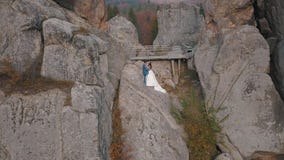 Newlyweds stand on a high slope of the mountain. Groom and bride. Arial view stock footage Newlyweds stand on a high slope of the mountain. Groom and bride. Arial view stock footage