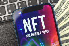 NFT crypto art logo on the screen close-up, background with laptop and money dollar bills