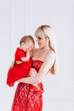 Nice, family, good photo of mother and daughter in red dresses in the studio. Mother`s Day and daughters. stock photo Nice, family, good photo of mother and daughter in red dresses in the studio. Mother`s Day and daughters. stock photo