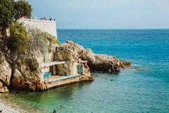 NICE, FRANCE - JUNE 26, 2017: People enjoying sunny weather on the stone beach of Mediterranean sea in Nice, near the Promenade de stock image NICE, FRANCE - JUNE 26, 2017: People enjoying sunny weather on the stone beach of Mediterranean sea in Nice, near the Promenade de stock image