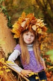Nice girl stands in autumn park leaning against a tree. At the head of woven wreath of autumn leaves royalty free stock image Nice girl stands in autumn park leaning against a tree. At the head of woven wreath of autumn leaves royalty free stock image