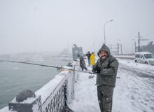 Niet geïdentificeerde mens die op de galatabrug vissen op een sneeuwdag in de winter stock fotografie Niet geïdentificeerde mens die op de galatabrug vissen op een sneeuwdag in de winter stock fotografie