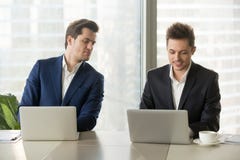 Nieuwsgierige zakenman die in het geheim collegalaptop het scherm bekijken, royalty-vrije stock foto's Nieuwsgierige zakenman die in het geheim collegalaptop het scherm bekijken, royalty-vrije stock foto's