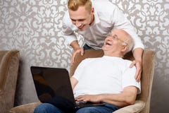 Nipote dietro suo nonno con il computer portatile immagine stock libera da diritti Nipote dietro suo nonno con il computer portatile immagine stock libera da diritti
