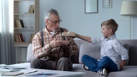 Nipote preoccupantesi che dà presente al nonno, all'attenzione ed alla cura per i cari immagine stock libera da diritti Nipote preoccupantesi che dà presente al nonno, all'attenzione ed alla cura per i cari immagine stock libera da diritti