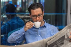 Nippender Kaffee des jungen Geschäftsmannes und Ablesenzeitung am Café stockfoto Nippender Kaffee des jungen Geschäftsmannes und Ablesenzeitung am Café stockfoto