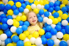 Niña feliz que se divierte en hoyo de la bola en centro interior del juego de los niños Niño que juega con las bolas coloridas en Fotos de archivo Niña feliz que se divierte en hoyo de la bola en centro interior del juego de los niños Niño que juega con las bolas coloridas en Fotos de archivo