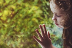 Niña rizada que mira hacia fuera la ventana de la gota de lluvia fotografía de archivo Niña rizada que mira hacia fuera la ventana de la gota de lluvia fotografía de archivo