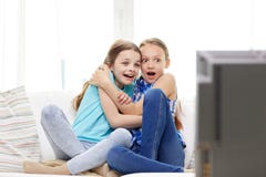 Niñas asustadas que miran horror en la TV en casa foto de archivo Niñas asustadas que miran horror en la TV en casa foto de archivo