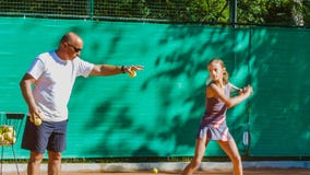 Niño de enseñanza del instructor o del coche cómo jugar a tenis en una corte interior almacen de video Niño de enseñanza del instructor o del coche cómo jugar a tenis en una corte interior almacen de video