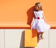 Niño de la moda de la calle, niña bonita en vestido con el bolso de la tienda Fotos de archivo libres de regalías Niño de la moda de la calle, niña bonita en vestido con el bolso de la tienda Fotos de archivo libres de regalías