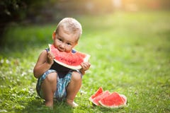 Niño lindo que come una rebanada de sandía foto de archivo libre de regalías Niño lindo que come una rebanada de sandía foto de archivo libre de regalías