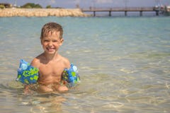 Niño pequeño en el mar con las sobre-mangas inflables imagen de archivo Niño pequeño en el mar con las sobre-mangas inflables imagen de archivo