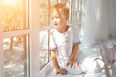 Niño pequeño lindo que mira en la ventana fotos de archivo libres de regalías Niño pequeño lindo que mira en la ventana fotos de archivo libres de regalías