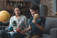 Niño pequeño y su madre que construyen un modelo de la Sistema Solar foto de archivo libre de regalías Niño pequeño y su madre que construyen un modelo de la Sistema Solar foto de archivo libre de regalías