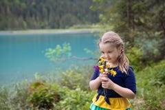 Niño que camina en campo de flor en el lago de la montaña fotos de archivo libres de regalías Niño que camina en campo de flor en el lago de la montaña fotos de archivo libres de regalías