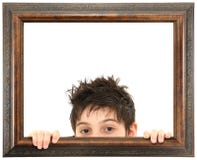 Niño que mira a escondidas de marco de madera adornado imagen de archivo libre de regalías Niño que mira a escondidas de marco de madera adornado imagen de archivo libre de regalías
