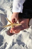Niño que sostiene una estrella de mar en la playa imagen de archivo Niño que sostiene una estrella de mar en la playa imagen de archivo