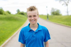 Niño rubio sonriente feliz joven del adolescente masculino del muchacho afuera en la sol del verano que lleva una camiseta azul Imagenes de archivo Niño rubio sonriente feliz joven del adolescente masculino del muchacho afuera en la sol del verano que lleva una camiseta azul Imagenes de archivo